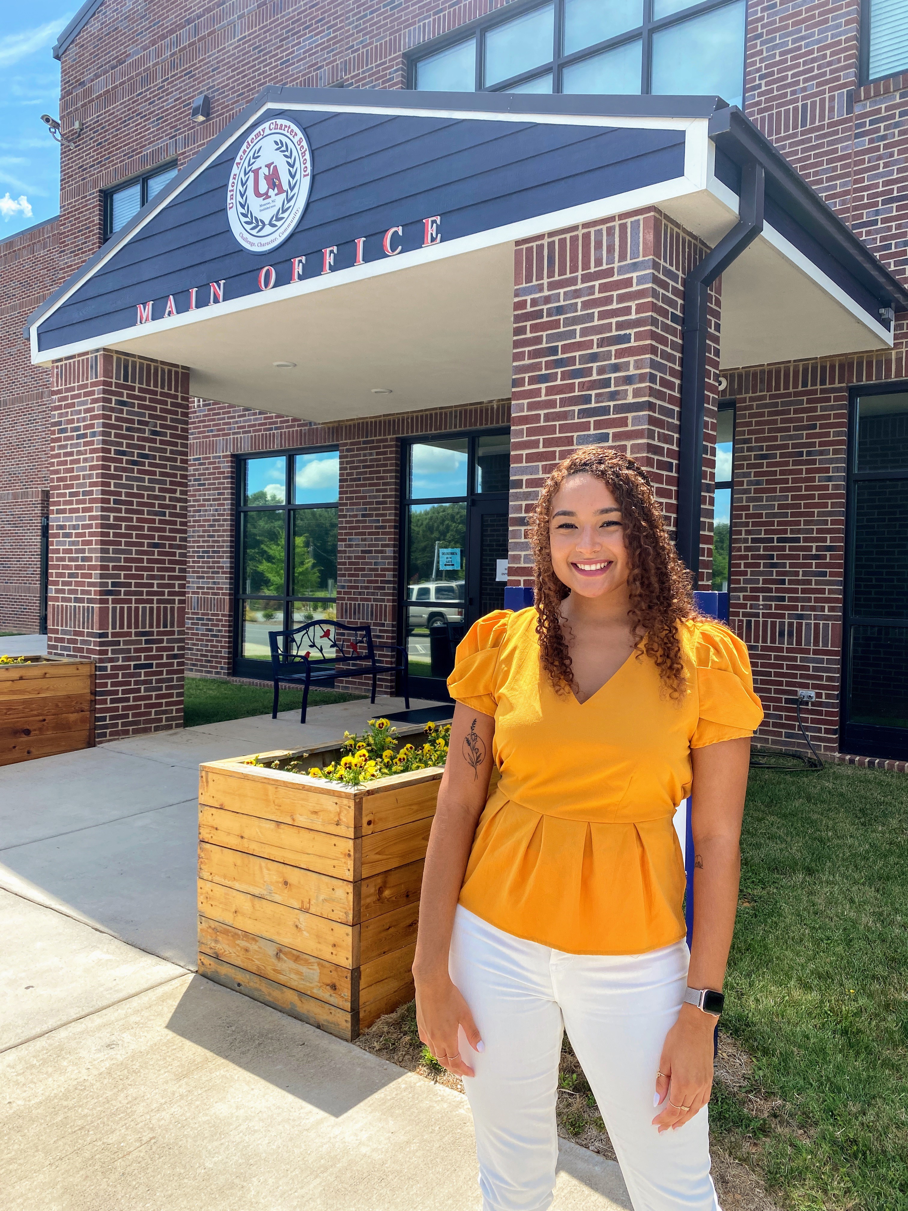 Union Academy teacher, Zöe Zander, standing in front of school building