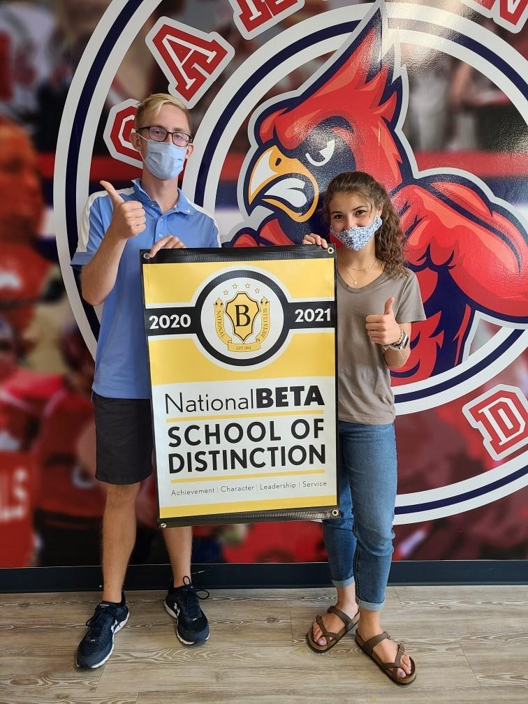 2 students giving thumbs up signs and holding a poster that says  National Beta School of Distinction 2020-2021